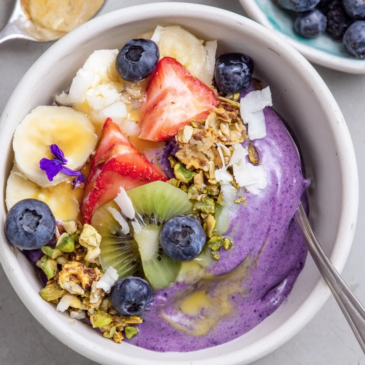 Vibrant smoothie bowls with pistachio and purple yam, topped with fresh berries.  