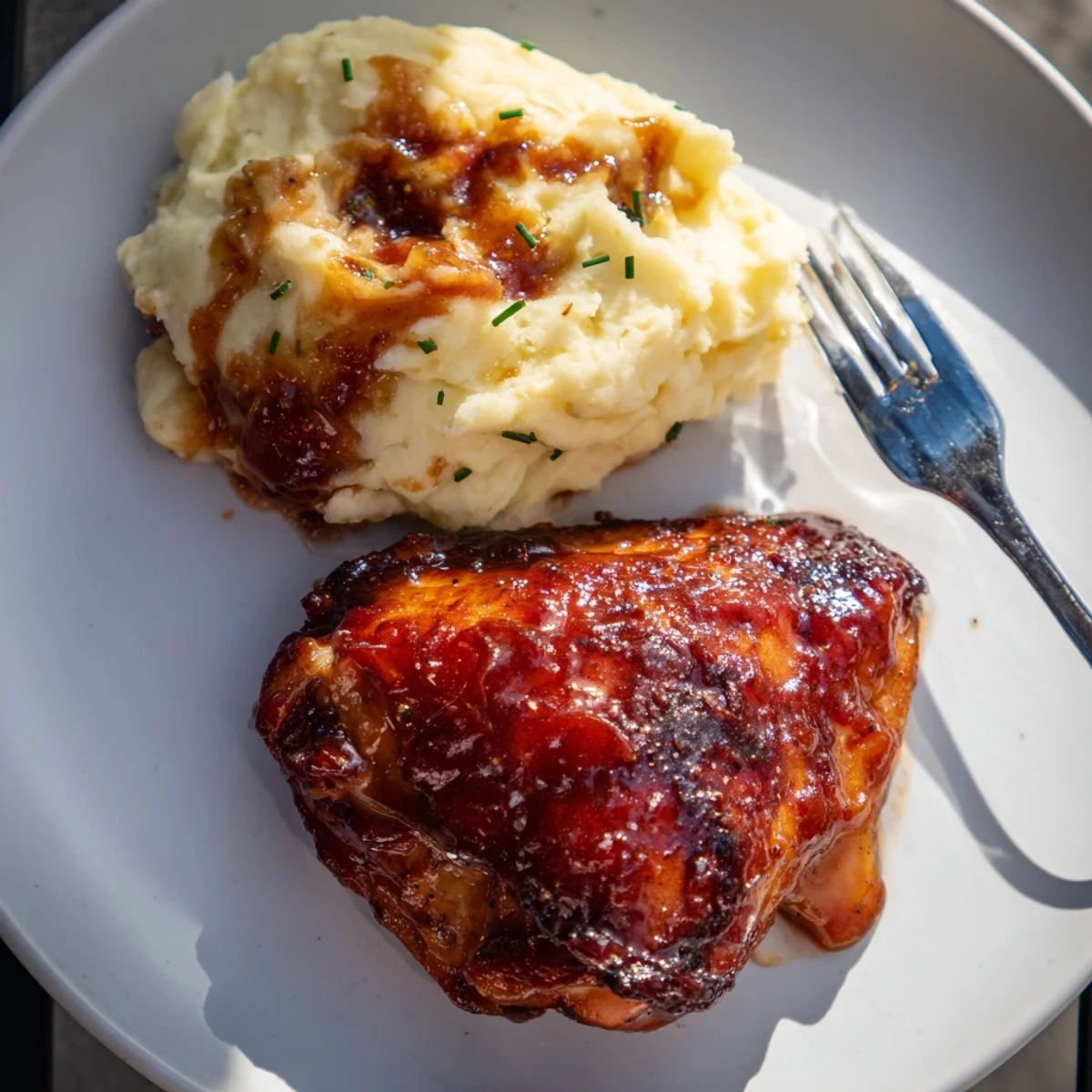 Succulent honey BBQ chicken thighs paired with creamy garlic mashed potatoes on a plate.  