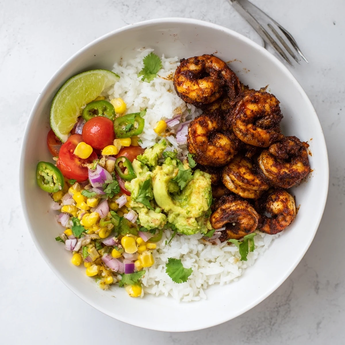A delicious Blackened Shrimp Bowl topped with creamy avocado corn salsa and rice.  