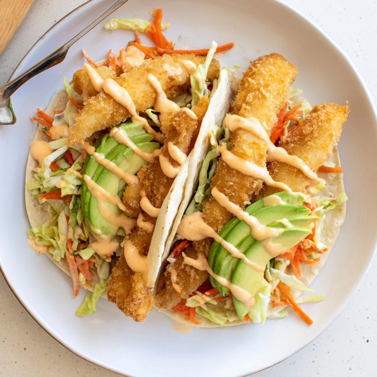 Close-up of fully assembled crispy fish tacos, showing flaky fish, cool slaw, ready to eat.