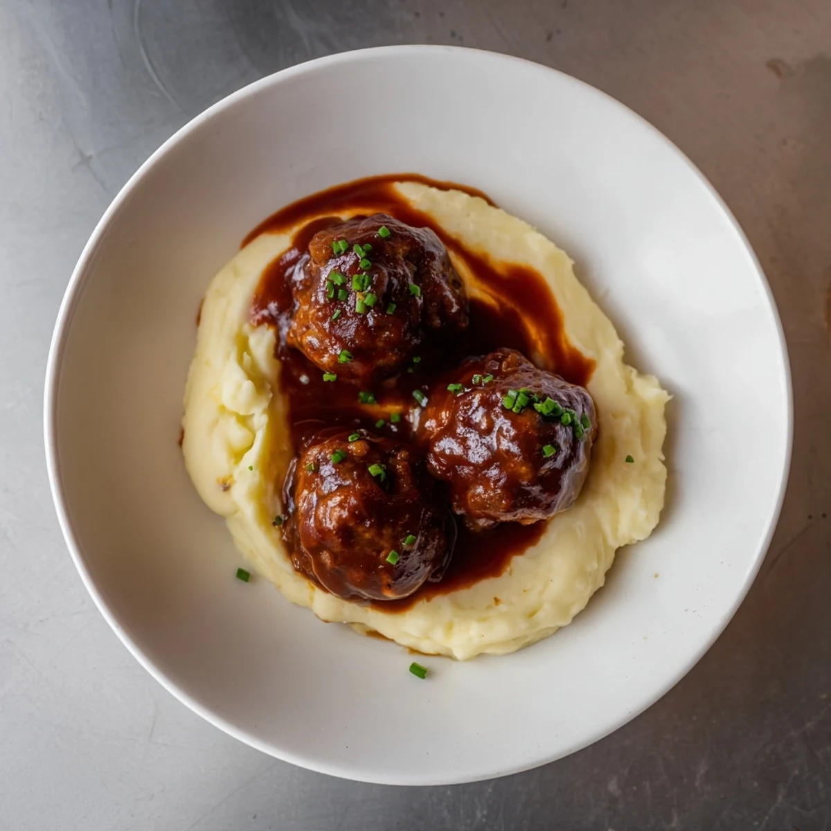 Smoky BBQ meatballs smothered in sauce, next to creamy mashed potatoes; a comforting family favorite.