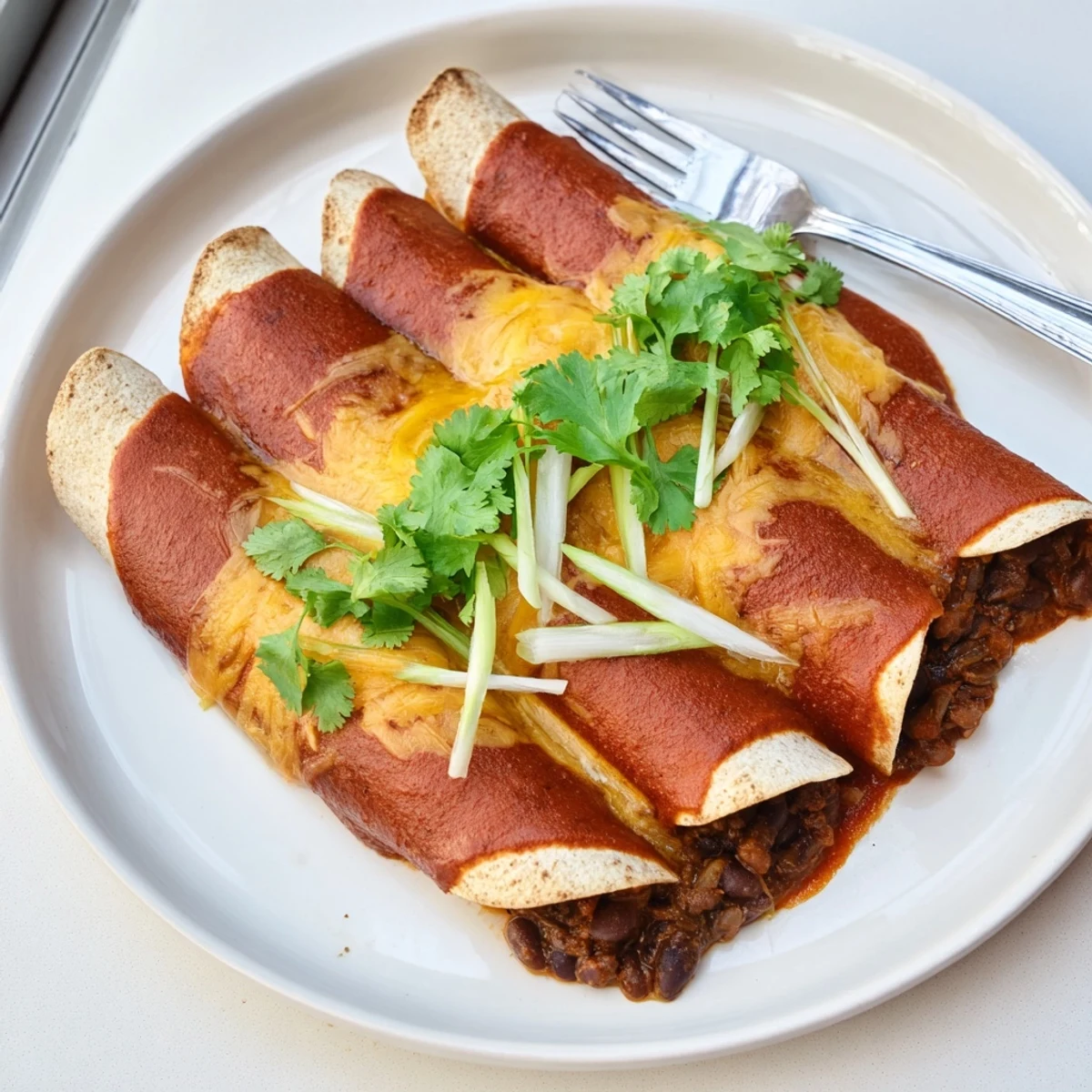 Warm Cheesy Bean Enchiladas bubbling with melted cheddar, a flavorful vegetarian main course.