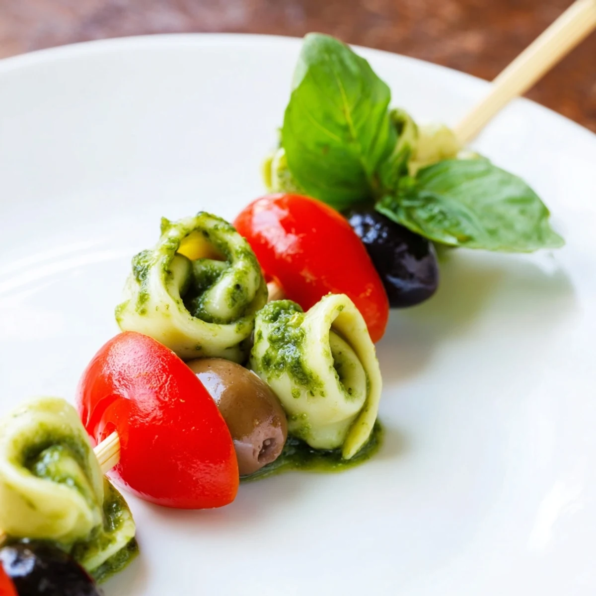 Savory Appetizer Skewers; featuring cooked tortellini, pesto, tomatoes, and olives perfect for your next gathering.