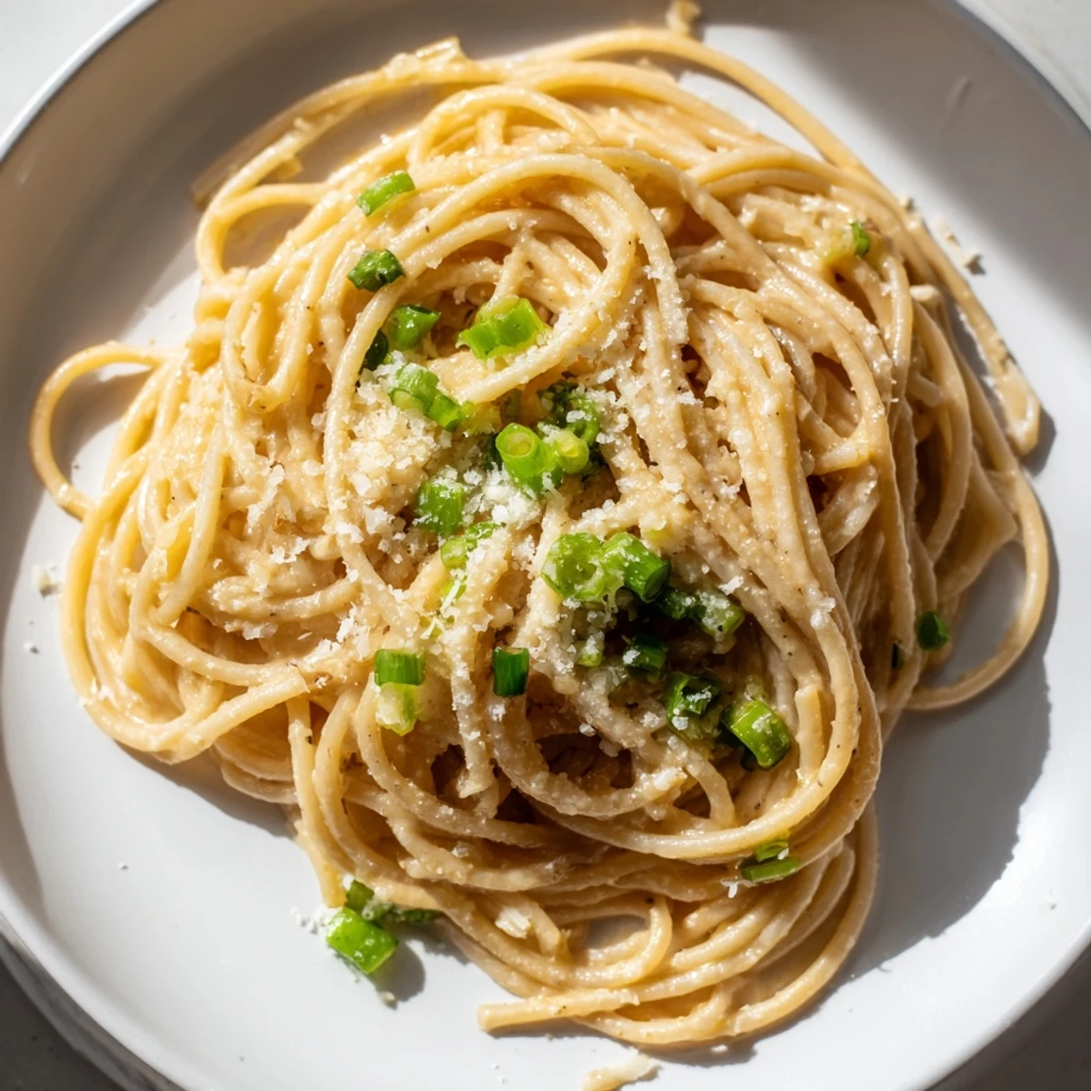 Golden, glossy miso butter pasta, perfectly plated and ready to enjoy with Parmesan cheese.