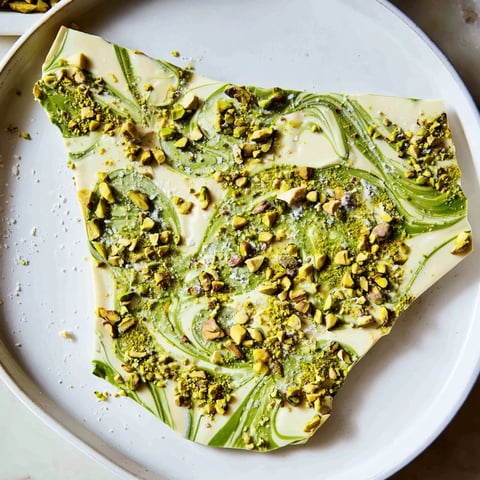 Creamy layers of Pistachio Matcha White Chocolate bark, swirled with green matcha and crunchy pistachios.