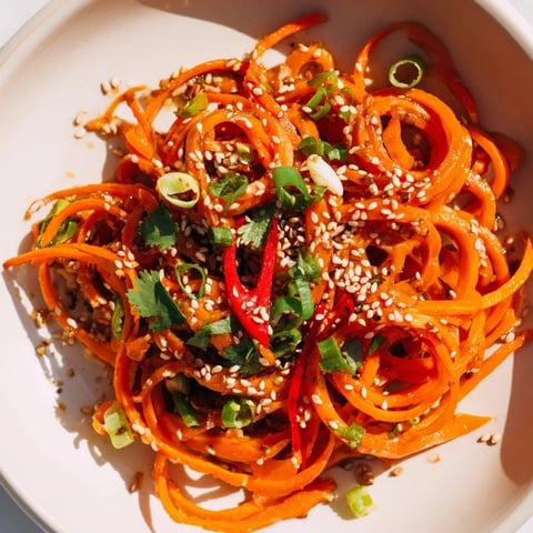 Vibrant Carrot Ribbon Salad Asian-Style tossed with a savory soy-sesame dressing, ready to eat now.