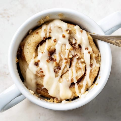 Close-up of delicious, fluffy Protein Cinnamon Roll Mug Cake, swirled with cinnamon and topped.
