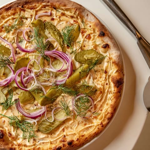 Delicious homemade Pickle Pizza topped with melted cheese and fresh dill hints.  