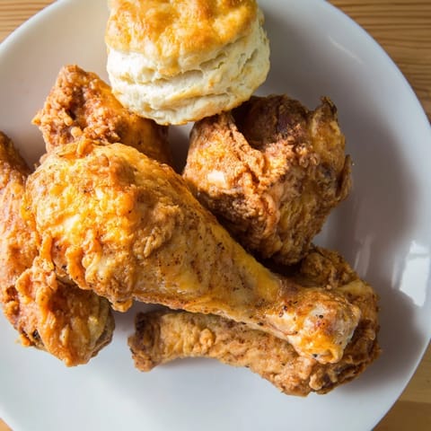 A close-up shot of crispy, perfectly cooked Southern Fried Chicken and tender buttermilk biscuits.