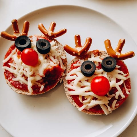 Warm, cheesy Reindeer Face Pizza Bagels, a fun holiday appetizer with a cherry tomato nose.