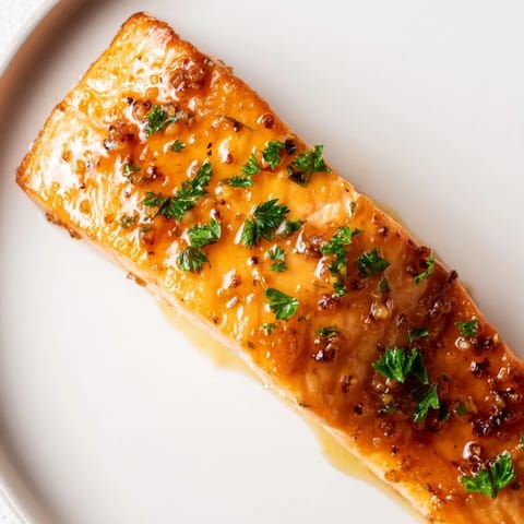 Juicy Honey Garlic Glazed Salmon with a caramelized glaze, served alongside lemon wedges and steamed rice.