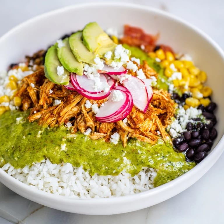 Close-up of a Green Enchiladas Rice Bowl featuring tender chicken and rice, drizzled with flavorful green sauce.