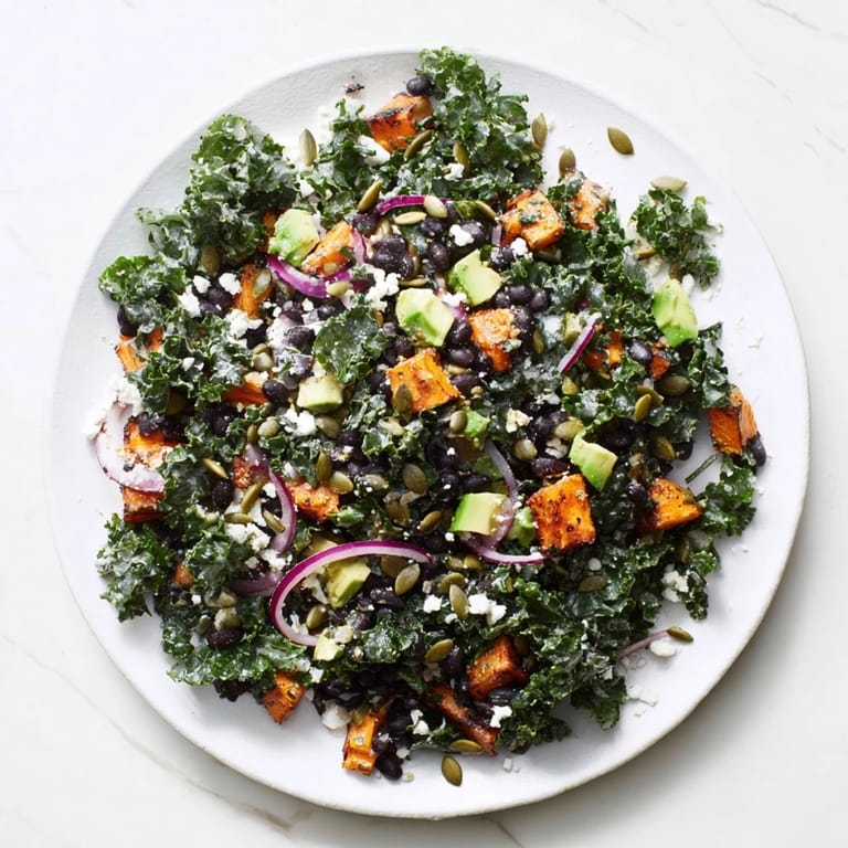 A bowl overflowing with massaged kale salad, featuring tender kale, black beans, and roasted sweet potato, ready to enjoy.