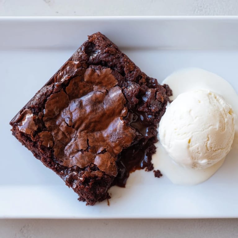 Molten Ina Garten Brownie Pudding served with vanilla ice cream, promising a rich, chocolate indulgence.